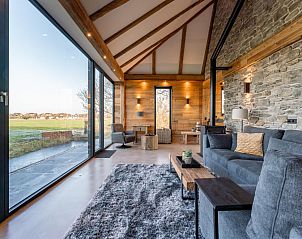 Interior of De Bonte Specht vacation home in Callantsoog with wooden interior and large windows.