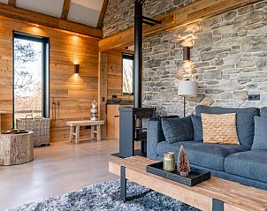 Cozy sitting area in De Bonte Specht vacation home, Callantsoog, with stone wall and wood stove.
