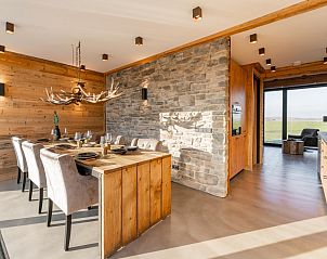Dining room in De Bonte Specht vacation home, Callantsoog, with sturdy wooden table and modern lighting.