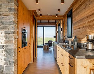 Modern kitchen of De Bonte Specht vacation home in Callantsoog, with wooden finish.