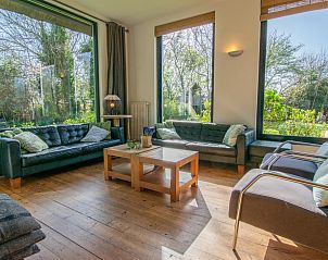 Gezellige woonkamer van Landhuis Duinzicht in Callantsoog, Noord-Holland met uitzicht op de groene tuin aan de Noordzeekust.