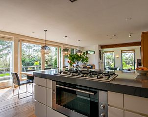 Ruime keuken met uitzicht op de tuin in Landhuis Duinzicht, een vakantiehuis in Callantsoog aan de Noordzeekust, Noord-Holland.