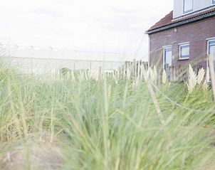 Exterior of Holiday home in Callantsoog, North Sea coast, North Holland, surrounded by dune grass.