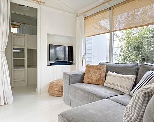 Lichte woonkamer van vakantiehuis Sol in Callantsoog met uitzicht op de tuin.