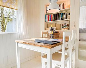 Gezellige eethoek in vakantiehuis Sol in Callantsoog met boekenplank.