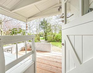 Uitzicht vanaf de veranda van vakantiehuis Sol in Callantsoog op groene tuin.