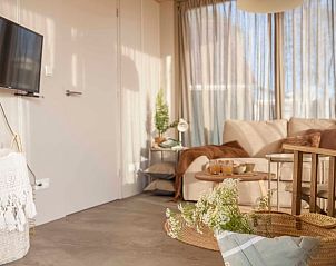 Moderne binnenruimte van Vakantiehuisje in Callantsoog, Noordzeekust, Noord-Holland met tv, bank en warme decoraties.