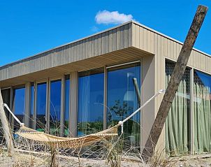 Buitenkant van Vakantiehuisje in Callantsoog, Noordzeekust, Noord-Holland met hangmat en grote ramen voor een ontspannen verblijf.