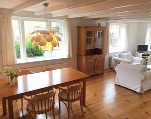 Ruime woonkamer van NH072 vakantiehuis in Groet, Noordzeekust, met comfortabele zithoek en boekenplanken.