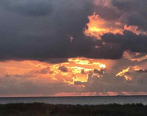 Woonkamer met boekenplanken en open haard in NH072 vakantiehuis, Groet, Noordzeekust.