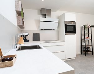 Eettafel en keuken in NH496 vakantiehuis Groet Noordzeekust met stijlvolle stoelen.