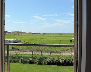 Uitzicht vanaf de Hooizolder in Camperduin, Noord-Holland met groene weiden en blauwe luchten.
