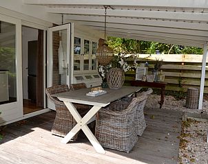 Gemtliche Veranda von Huisje in Egmond aan den Hoef, Ferienhaus an der Nordseekste in Nordholland, mit stilvollen Rattansthlen.