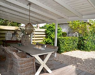 Gemtliche Veranda im Haus in Egmond aan den Hoef, Ferienhaus an der Nordseekste, Nordholland, mit rustikalen Mbeln und grner Umgebung.