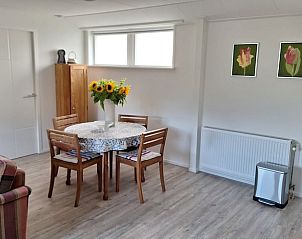 Eethoek in Vakantiehuisje in Egmond aan den Hoef met bloemen op tafel, knusse sfeer in Noord-Holland.