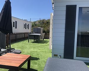 Ruim terras van Zee en duin chalet, IJmuiden, met tuinmeubilair aan de Noordzeekust van Noord-Holland.