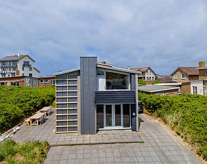 Beachhouse II in Bergen, Noord-Holland, modern vakantiehuis aan de Noordzeekust met zonnig terras en omringd door groene duinen.