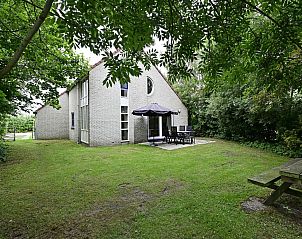 Terras van vakantiehuis in Julianadorp aan Zee met tuinmeubilair en parasol.