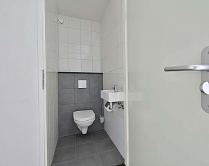 Modern toilet met witte tegels in vakantiewoning Julianadorp aan Zee.