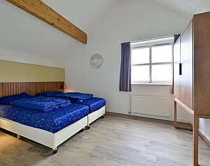 Slaapkamer met houten balken en tweepersoonsbed in Julianadorp aan Zee.