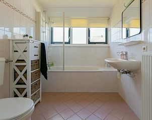 Badkamer met bad en douche in vakantiewoning Julianadorp aan Zee.