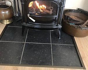 Gezellige houtkachel in de woonkamer van Huis op Duynopgangh, vakantiehuis in Julianadorp aan de Noordzeekust.