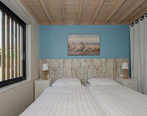 Sfeervolle slaapkamer in Sea House Family vakantiehuis, Overveen, met stranddecor en houten plafond, ideaal voor een ontspannen verblijf.