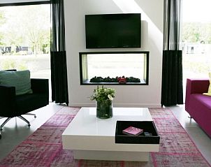 Stijlvolle woonkamer in Droompark Spaarnwoude vakantiehuis, Halfweg, met open haard en uitzicht op de natuur.