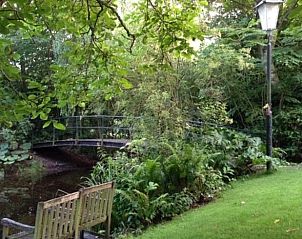 Romantische brug bij Vakantiehuis in Andijk, omgeven door weelderige natuur en rust.