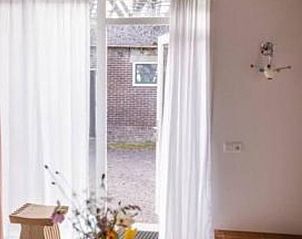 Lichte entree van Vakantiehuis in Hem, Noord-Holland met uitzicht op de tuin.