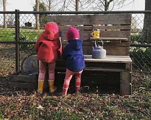 Kinderen spelen in de tuin van Vakantiehuis in Hem, Noord-Holland met houten bank.