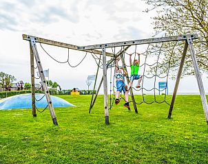 Kinderen spelen in de speeltuin bij Vakantiehuis Pavilion Waterfront 4 in Bovenkarspel, Noord-Holland aan de IJsselmeerkust.