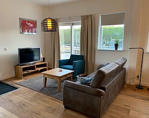 Gezellige woonkamer in De oude Paardenstal, appartement aan de Noordzeekust, met comfortabele banken en een flatscreen-tv.