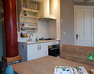 Moderne keuken in Huisje in Oudesluis, vakantiehuis in Noord-Holland, compleet met fornuis en houten eettafel.