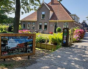Buitenkant van Huisje in Oudesluis, vakantiehuis in Noord-Holland, met kleurrijke bloemen en uitnodigende entree.