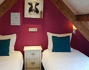 Sfeervolle tweepersoonskamer in Vakantiehuis in Oudesluis, Noord-Holland met houten balken.