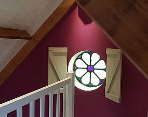 Trap naar bovenverdieping met glas-in-loodraam in Vakantiehuis in Oudesluis, Noord-Holland.