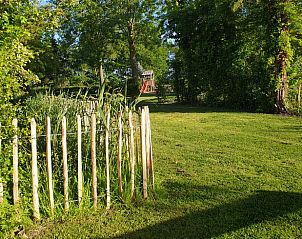 Groene tuin met speelruimte in Vakantiehuis in Oudesluis, Noord-Holland, ideaal voor kinderen.