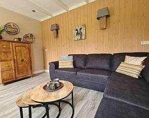 Gezellige woonkamer in Huisje in Oudesluis, vakantiehuis in Noord-Holland met comfortabele bank en houten kast.