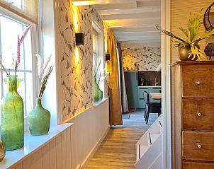 Lichte gang in Huisje in Oudesluis, vakantiehuis in Noord-Holland met decoratieve vazen en houten meubels.