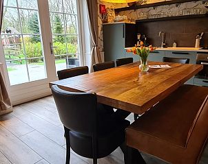 Eetruimte in Huisje in Oudesluis, vakantiehuis in Noord-Holland met grote houten tafel en uitzicht op tuin.