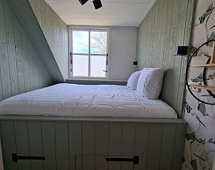 Knusse slaapkamer in Huisje in Oudesluis, vakantiehuis in Noord-Holland met comfortabel bed en houten interieur.