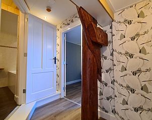 Unieke gang in Huisje in Oudesluis, vakantiehuis in Noord-Holland met houten balk en moderne deuren.