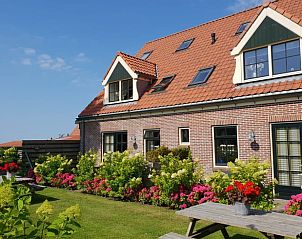 Buitenkant van Vakantiehuisje in Oudesluis met kleurrijke tuin, perfect voor een ontspannen verblijf in Noord-Holland.