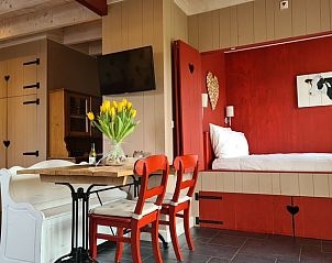 Eetruimte in Vakantiehuisje in Oudesluis, Noord-Holland met gezellige houten meubels en frisse bloemen.