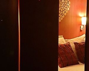 Sfeervolle slaapkamer in Vakantiehuisje in Oudesluis, Noord-Holland met warme verlichting en comfortabele kussens.