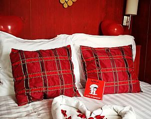 Gezellige slaapkamer in Vakantiehuisje in Oudesluis met rode accenten, voor een romantische sfeer in Noord-Holland.