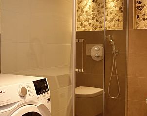Moderne badkamer in Huisje in Schoorl, Noord-Holland met luxe douche en wasmachine, ideaal vakantiehuis voor comfort en ontspanning.