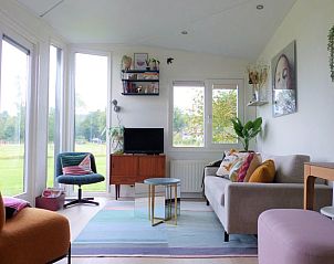 Cozy living room of Holiday Home in Schoorl, North Holland, with views of the green surroundings and a comfortable seating area.