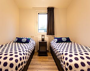 Gezellige slaapkamer met twee bedden in Waterlodge, een vakantiehuis in Berkhout, Noord-Holland, ideaal voor een ontspannen verblijf.